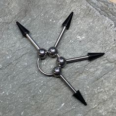 four pointed balls and two black spikes on a gray rock with one ball in the middle