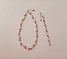 a pink and green beaded necklace on a white surface