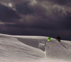 a person riding skis on top of a snow covered slope under a cloudy sky