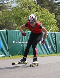 a man riding a skateboard down a street next to a green fence and trees