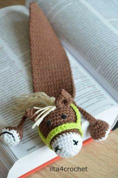 a crocheted bookmark laying on top of an open book with a horse head