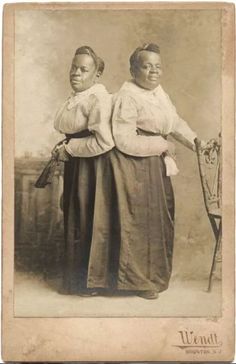 an old black and white photo of two women standing next to each other, one holding a cane