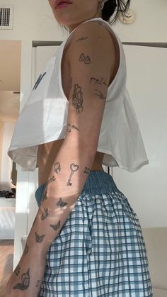 a woman with tattoos on her arm and arms is standing in front of a mirror