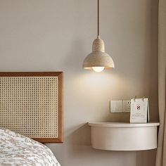 a bedroom with a bed, nightstand and hanging light fixture in the corner between two windows