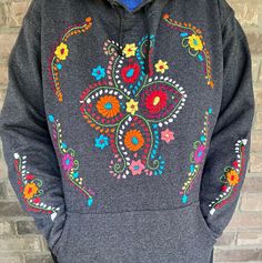 This colorful sweatshirt is perfect to keep warm, comfortable, and stylish during the cold winter months. They have hand embroidered details on both sleeves, front center, and on the hoodie. This sweatshirt is hand embroidered by Mexican Artisans and each can take up to a week for one person to finish!  Each sweater is 50% cotton/50% polyester.  Please choose a size in the drop down menu. You will receive a sweatshirt with the same pattern as the picture, however, the colors may differ as they a Casual Hooded Hoodie With Floral Embroidery, Casual Winter Sweater With Floral Embroidery, Floral Embroidery Long Sleeve Hoodie For Fall, Embroidered Hooded Sweatshirt For Winter, Winter Embroidered Crew Neck Hoodie, Hooded Embroidered Sweatshirt For Winter, Casual Embroidered Winter Sweater, Hooded Winter Sweatshirt With Embroidered Graphics, Casual Embroidered Sweater For Winter