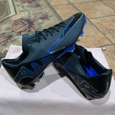 a pair of black and blue soccer shoes sitting on top of a white cloth covered table