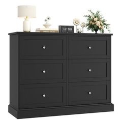 a black dresser with drawers and flowers on top