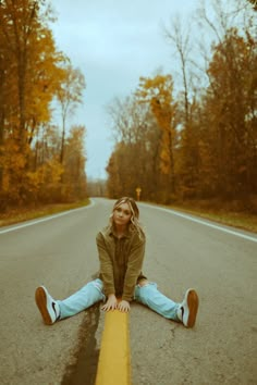 a woman sitting on the side of a road with her legs crossed in front of her