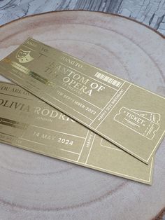 two gold tickets sitting on top of a wooden plate