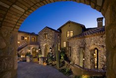 the entrance to a large house with stone walls and arched doorways at night time