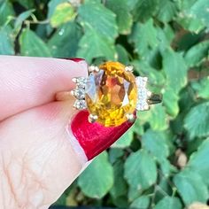 a woman's hand holding an orange and yellow ring with white diamonds on it