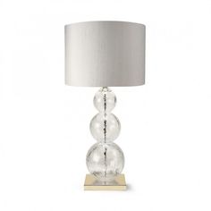 a clear glass table lamp with a silver shade on the base and a light grey fabric lampshade