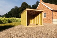 a small wooden shed sitting in the middle of a gravel field next to a brick building