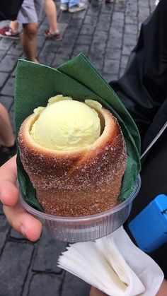 a person holding up a cupcake with ice cream in it's center on a street