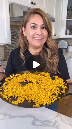 a woman holding up a pan filled with yellow flowers in the middle of a kitchen