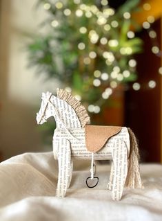 a toy horse made out of books sitting on top of a white sheet with lights in the background