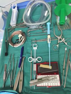 an assortment of medical supplies laid out on a green cloth with scissors, pliers and other items