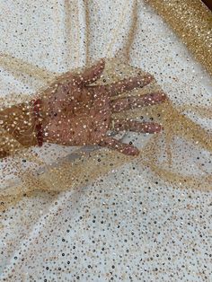 an image of a hand that is covered in gold sequins on a white cloth