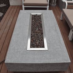 an outdoor fire pit on a deck with lounge chairs and tables in the back ground