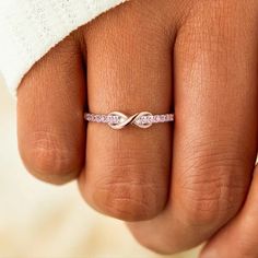 a woman's hand with a pink diamond ring on top of her finger and a white towel in the background