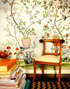 a chair sitting in front of a wall with flowers and birds painted on the walls