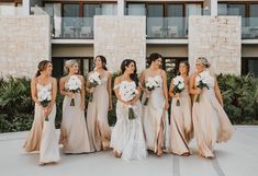 a group of women standing next to each other in front of a building with flowers