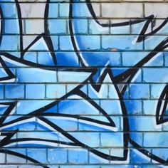 graffiti on a brick wall with blue and black spray painted over the top in different colors