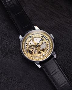 This customized Pobeda watch, with a 37 mm case, boasts a mesmerizing handcrafted skeleton dial that captures the beauty of celestial motifs. The intricate golden patterns etched into the dial evoke images of the cosmos, giving the timepiece an artistic and ethereal quality. The open-worked design of the dial not only enhances its aesthetic appeal but also provides a fascinating view of the inner mechanical workings, making it a true conversation piece. The watch's case is made from polished stainless steel, offering both durability and a sleek, modern look that contrasts beautifully with the ornate dial. This sturdy 37 mm case frames the celestial motif perfectly, ensuring that the dial remains the centerpiece of the design. Paired with a classic black leather strap, the watch exudes soph Luxury Automatic Watch Accessories For Gift, Steampunk Silver Watch With Skeleton Dial, Luxury Automatic Watch As Gift, Gold Steampunk Watch With Skeleton Dial, Steampunk Automatic Watch For Formal Occasions, Black Watches With Rotating Bezel For Gifts, Steampunk Watch With Skeleton Dial, Antique Skeleton Dial Watch For Formal Occasions, Silver Steampunk Watch For Formal Occasions