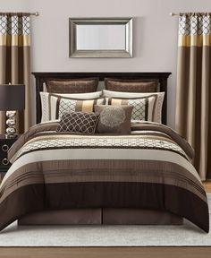 a bed with brown and tan comforters in a bedroom next to a mirror on the wall