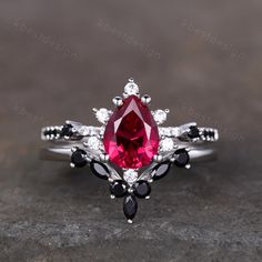 a close up view of a ring with a red stone and black stones on it