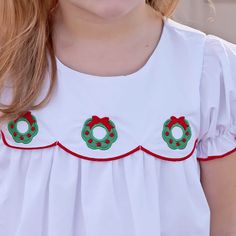 Be in the festive spirit with our Christmas Wreath Bailey Dress. Features an embroidered Christmas wreath on a solid white fabric. Cute bishop sleeves with red trim. This scalloped dress is sweet and traditional. Christmas Wreath White, Embroidered Christmas, Scalloped Dress, Scalloped Hem, White Fabric, White Fabrics, Christmas Wreath, Christmas Time, Christmas Wreaths