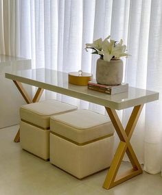 a table with two stools and a flower vase on it in front of a window