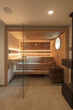 a wooden sauna in the middle of a room with glass walls and flooring