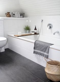 a bathroom with a toilet, bathtub and towel on the shelf next to the tub