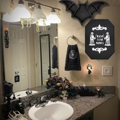 a bathroom decorated for halloween with bats on the wall and lights hanging from the ceiling