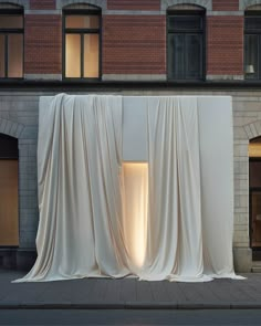 a white curtain draped over a sidewalk in front of a building