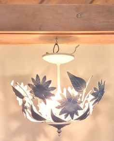 a chandelier hanging from the ceiling with flowers and leaves on it's glass