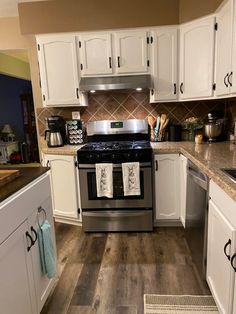 a kitchen with white cabinets and stainless steel appliances