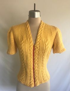 Adorable buttercup yellow 1940's reproduction soft chunky knit cabled cardigan! This was made from an original 1940's knitting pattern. Yarn is new, but red zipper is vintage. The yarn is ever so soft cotton, rayon, bamboo. It is cool to the touch. Cable pattern runs around the neck and down the front, under the bust and at the center of the sleeves.  Worn once, but it is clean and in excellent condition! Some very light pilling at the underarms. Made by yours truly! Measurements: would best fit Fitted Yellow Knit Sweater, Yellow Fitted Knit Sweater, Vintage Knitted Spring Cardigan, Fitted Vintage Knitted Cardigan, Fitted Vintage Knit Outerwear, Cozy Fitted Hand-knitted Cardigan, Cozy Fitted Hand Knitted Cardigan, Hand Knitted Fitted Tops For Fall, Fitted Yellow Knitted Sweater