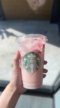 someone holding up a cup of strawberry milkshake