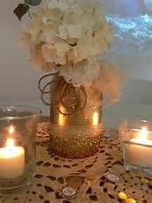 a table topped with candles and flowers on top of a doily covered table cloth