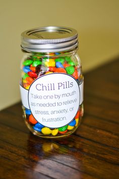 a glass jar filled with lots of colorful candies on top of a wooden table