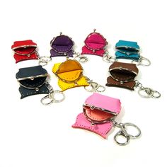 six different colored leather purses with key chains attached to each other on a white surface