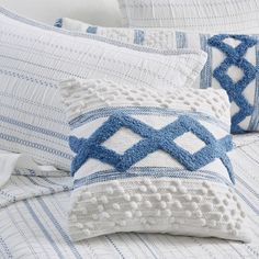 two blue and white pillows sitting on top of a bed next to eachother