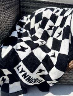 a black and white checkered blanket sitting on top of a wicker basket next to a wooden stick