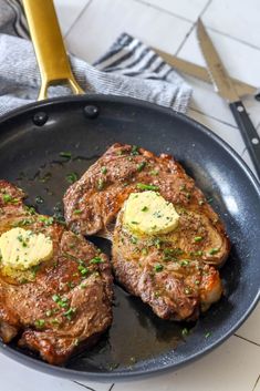 two steaks are being cooked in a skillet with butter and chives on top