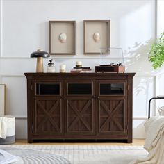 a living room with two framed pictures on the wall and a wooden cabinet in front of it