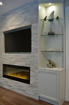 a living room with a fireplace and shelves filled with items on top of the wall