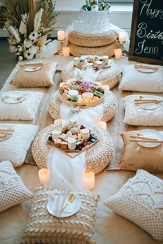 a table topped with lots of food next to pillows and candles on top of it