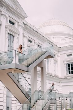 two people are standing on the stairs in front of a large white building with a domed roof